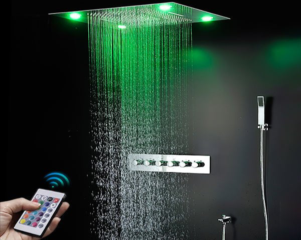 Modern rainfall shower with green LED lighting, a wall-mounted control panel, and a hand holding a color-changing remote.