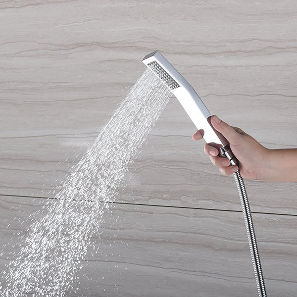 Hand-held chrome shower spraying water against a beige tiled wall.