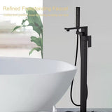 Black freestanding faucet next to a white bathtub with a plant in the background
