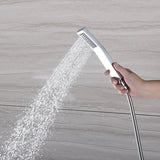 Hand-held chrome shower spraying water against a beige tiled wall.